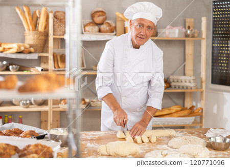 Elderly male baker cutting dough with scraper Elderly male baker cutting dough with scraper 120771096