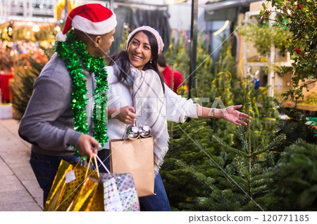 Positive woman and man buying Christmas tree and toys at Christmas Fair 120771185