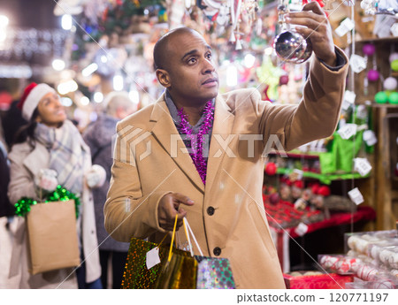 Portrait of man customer near counter with Christmas gifts in evening time 120771197