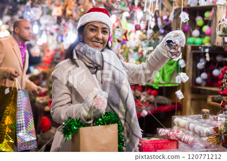 Portrait of woman customer near counter with Christmas gifts in evening time 120771212