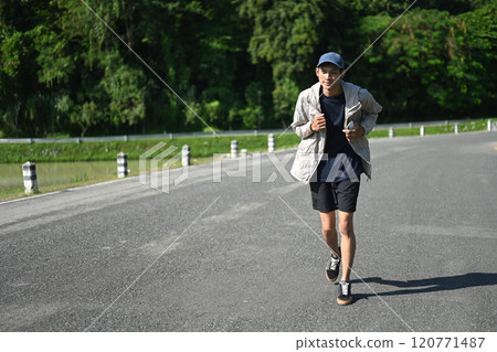 Young sporty man jogging along a road nearby pond on sunny day Young sporty man jogging along a road nearby pond on sunny day 120771487