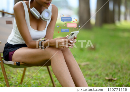 Young woman scrolling through mobile phone with social media notifications while relaxing after her workout Young woman scrolling through mobile phone with social media notifications while relaxing after her workout 120771556