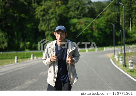 Young man jogging along a road nearby pond and taking in the fresh air Young man jogging along a road nearby pond and taking in the fresh air 120771561
