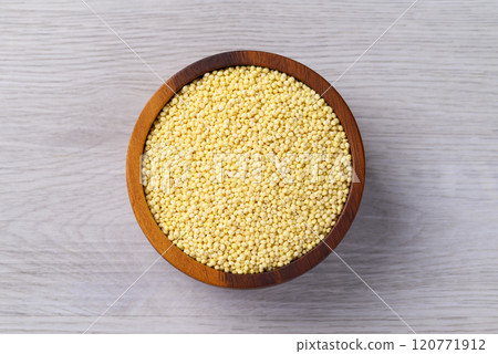 Organic yellow millet grain in wooden bowl on white table, Healthy food ingredient, Top view 120771912