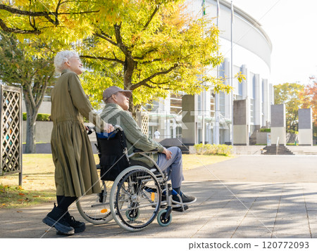 Senior couple: man in wheelchair and woman assisting him 120772093