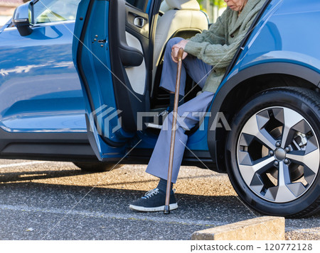 Senior man with a cane getting out of a car 120772128