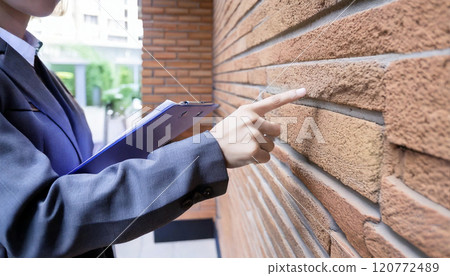 Workers inspecting the exterior walls of a house Workers inspecting the exterior walls of a house 120772489