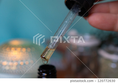Drip of essential oil from pipette to brown bottle.Closeup 120772630