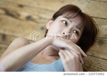 一個留著短鮑伯的年輕女子躺在地板上 120772662