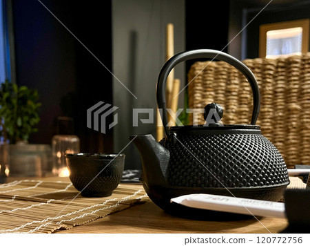 Black teapot and kettle on a wooden table with cups for tea in a Asian tea and sushi house Black teapot and kettle on a wooden table with cups for tea in a Asian tea and sushi house 120772756