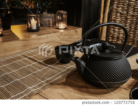 Black teapot and kettle on a wooden table with cups for tea in a Asian tea and sushi house Black teapot and kettle on a wooden table with cups for tea in a Asian tea and sushi house 120772758