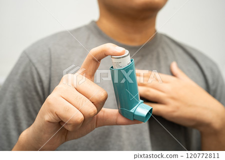 Asthma and chronic obstructive pulmonary disease COPD, Asian young man using metered dose inhaler MDI. 120772811