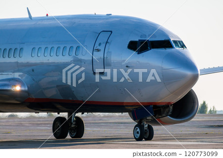 Close-up the front of the passenger plane taxiing on the airport apron 120773099