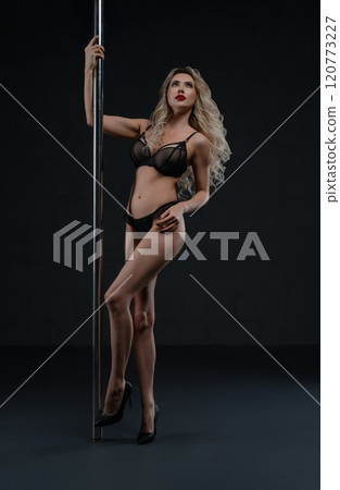 Woman dances gracefully on a pole in a dimly lit space 120773227