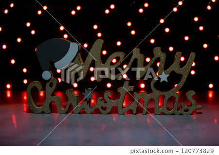 Merry Christmas wooden message on dark bokeh light garland background. New year and Christmas preparation. Handmade eco-friendly decor. Sustainable 120773829