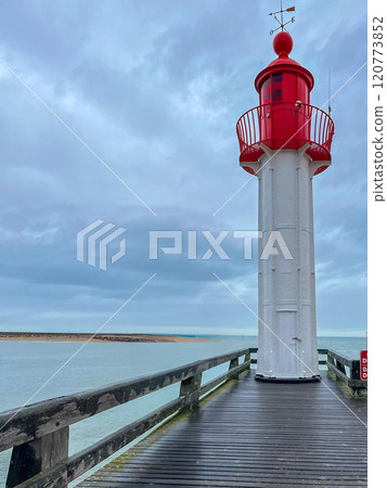 Red lighthouse with wooden pier with blue sky with rainy clouds background in the Normandia, France 120773852