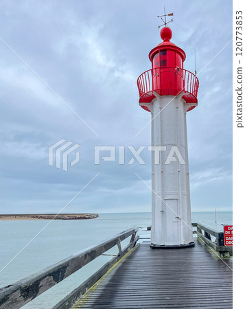 Red lighthouse with wooden pier with blue sky with rainy clouds background in the Normandia, France 120773853