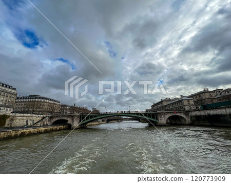 River Seine in Paris, France. Beautiful cityscape with cloudy sky with the view on the houses and bridge from a boat. River Seine in Paris, France. Beautiful cityscape with cloudy sky with the view on the houses and bridge from a boat. 120773909