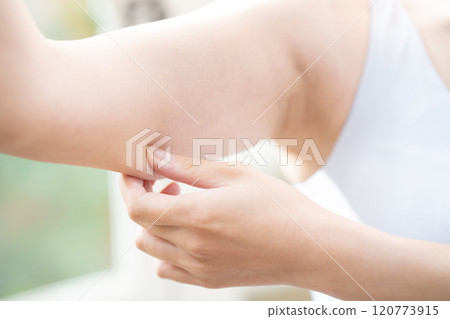 一位女士正在檢查上臂的鬆弛情況 [零件切割] 120773915