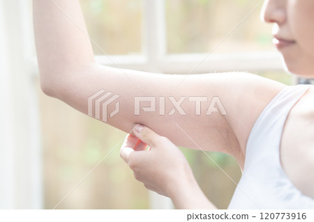 一位女士正在檢查上臂的鬆弛情況 [零件切割] 120773916