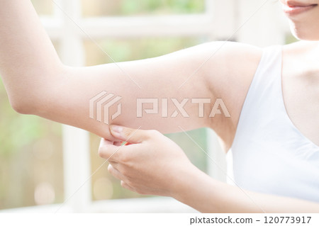 A woman checking the slack in her upper arm [Parts cut] 120773917