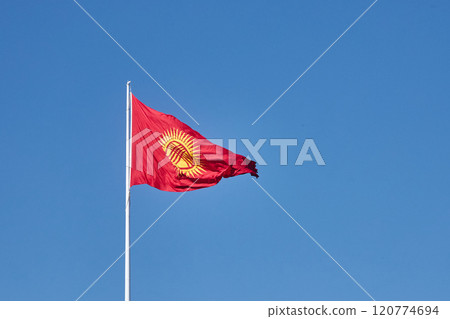 Kyrgyzstan updated flag flutters against the clear blue sky. 120774694