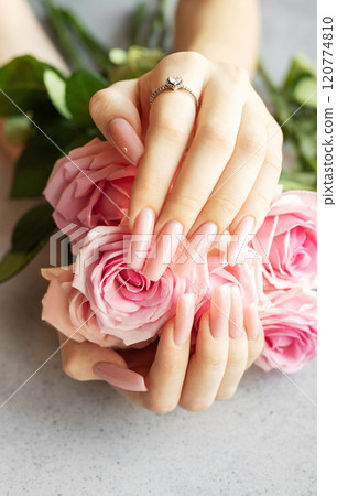 Woman showing pink manicure and diamond ring holding bouquet of roses 120774810