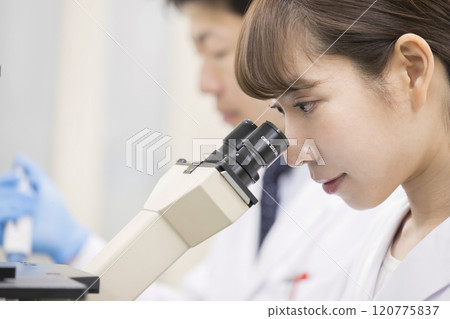 研究開發實驗圖像一位年輕的女性研究員，通過顯微鏡看 120775837