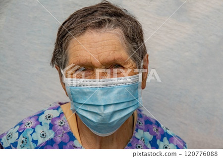 Senior woman wear disposable medical mask on her aged face. Elderly woman in single-use mask. Aged wrinkled face of 80 year old woman with short gray haircut 120776088