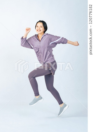 Full body photo of a woman in sportswear jumping 120776182