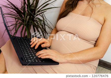 Expecting mother using nasal spray while working on laptop 120776476