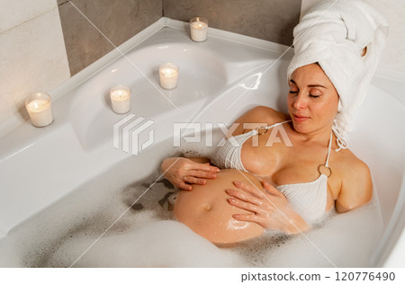 Pregnant woman in bubble bath with candles 120776490