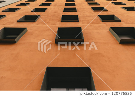 Contemporary building with terracotta color wall and rows of windows in metal frames. Modern architecture of Berlin Germany. Low angle view to facade exterior. Urban geometric pattern 120776826