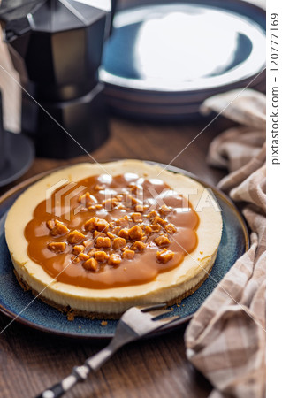 Cheesecake with caramel topping on plate on wooden table. 120777169