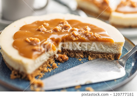 A cut piece of  cheesecake with caramel topping on plate on kitchen table. 120777181