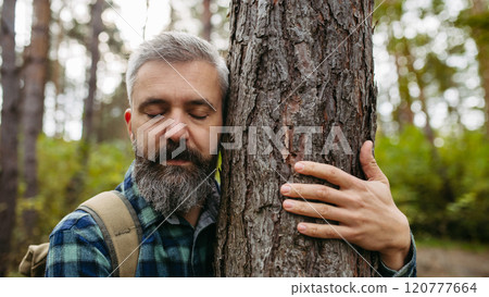 Handsome man standing in the middle of nature with closed eyes, hugging tree. Peaceful atmosphere of the forest, forestbathing. Handsome man standing in the middle of nature with closed eyes, hugging tree. Peaceful atmosphere of the forest, forestbathing. 120777664