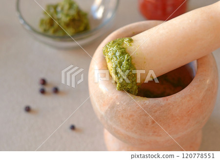 Marble mortar with pesto sauce on kitchen table. Top view. Cooking, spices and healthy eating. Traditional dishes of Italy.  120778551