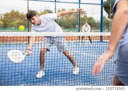 Male player ready to hits the ball while playing padel on hard court 120778565