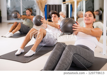 Young woman doing pilates with ball 120778613