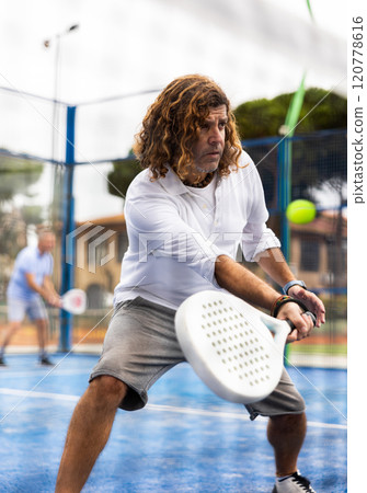 View through net of man playing paddle tennis outdoor View through net of man playing paddle tennis outdoor 120778616