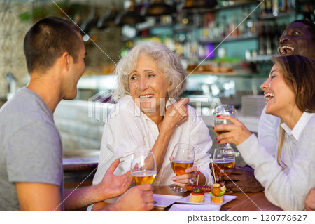 Cheerful family celebrating meeting or acquaintance with beer in bar. Focus on elderly woman Cheerful family celebrating meeting or acquaintance with beer in bar. Focus on elderly woman 120778627