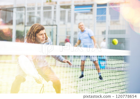 Portrait of middle-aged Latin male in sportswear enjoying popular sport padel game on tennis court outside Portrait of middle-aged Latin male in sportswear enjoying popular sport padel game on tennis court outside 120778654
