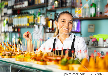 Female bartender offering delectable sandwiches pinchos in bar Female bartender offering delectable sandwiches pinchos in bar 120778680