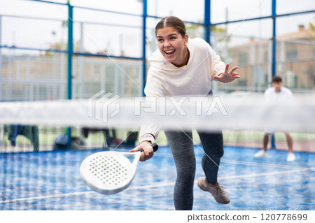 Sporty young girl playing padel on open court Sporty young girl playing padel on open court 120778699