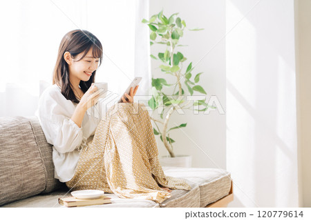 Woman watching smartphone while drinking coffee Woman watching smartphone while drinking coffee 120779614
