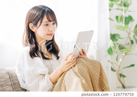 坐長沙發和觀看片劑的婦女 120779750