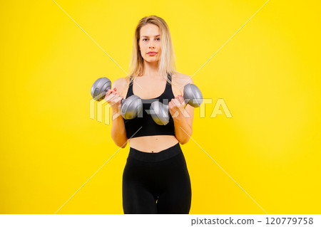 Muscular woman doing exercises with dumbbells at biceps. Photo of strong female isolated on studio 120779758