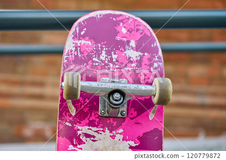 Used scratched pink skateboard against stone wall at city street. Urban sport and youth subculture concept Used scratched pink skateboard against stone wall at city street. Urban sport and youth subculture concept 120779872