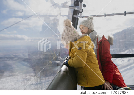 Father and young son on a winter holiday is riding cable car to the top of the mountain. 120779881