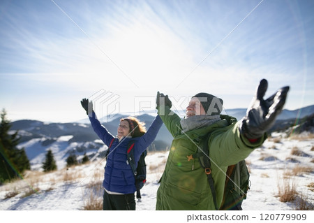 Portrait of active seniors standing in the middle of winter nature with open arms. 120779909